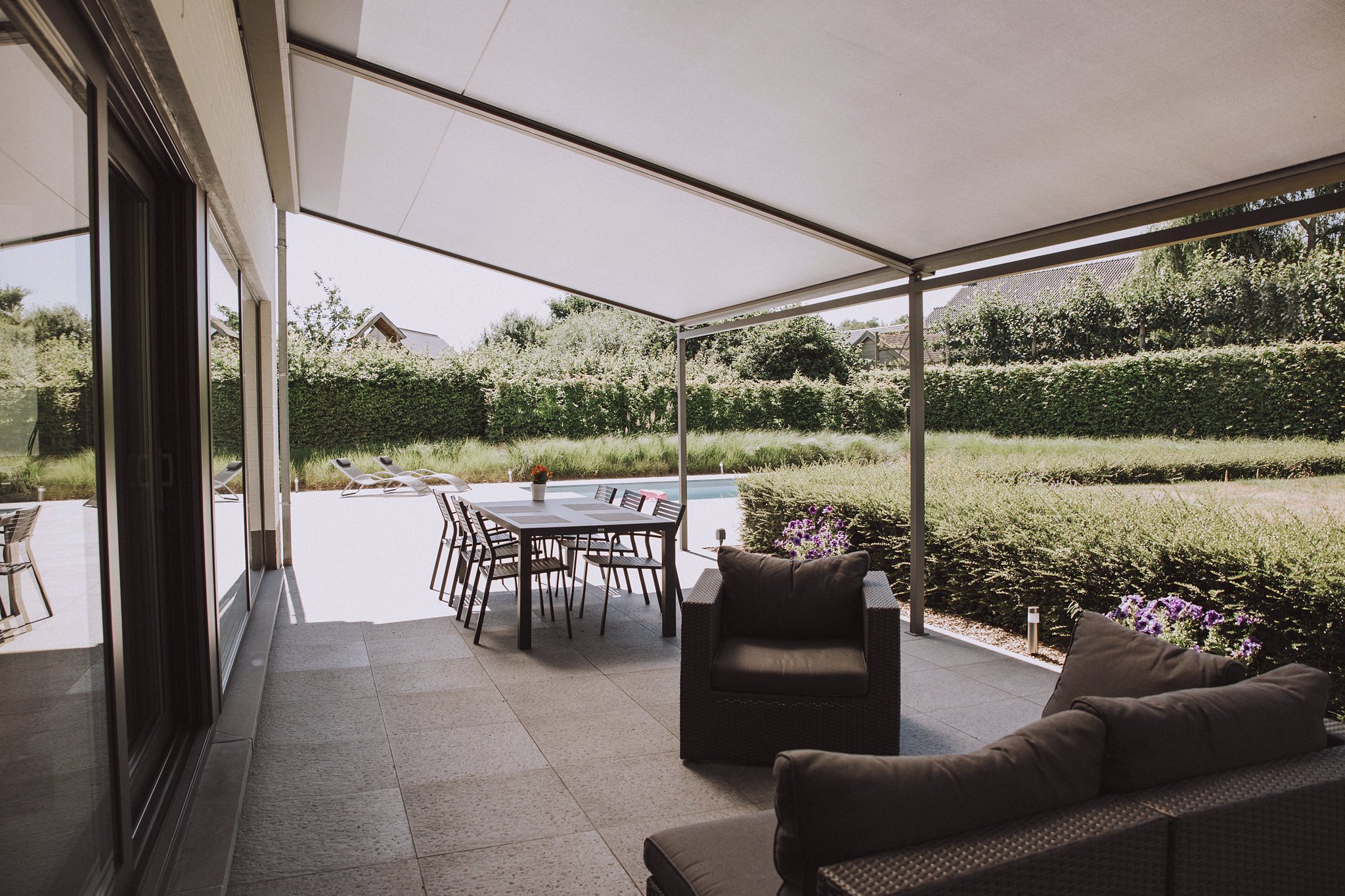 Textilní pergola VELANI se stahovací střechou na terase. Doplněk zvyšující komfort terasy.