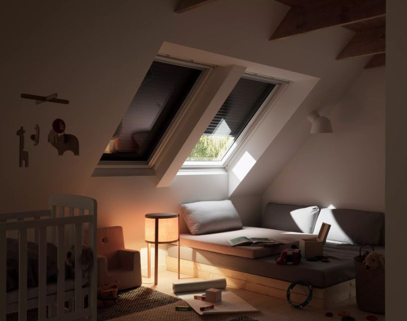 Střešní okno VELUX se staženou venkovní stínicí roletou proti prudkému slunečnímu svitu.