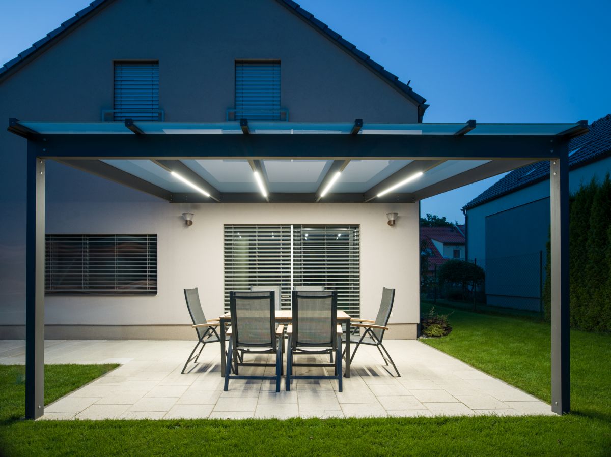 Skleněná pergola GLASETTI s integrovaným LED osvětlením v teplé žluté barvě pro večerní posezení.
