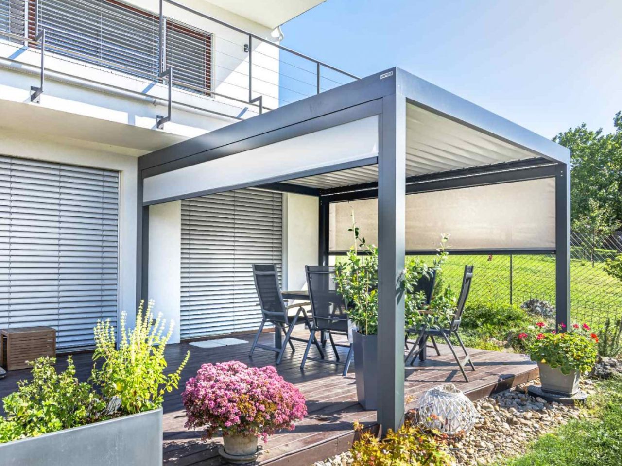 Moderní hliníková pergola v odstínu z barevného vzorníku RAL, laděná s fasádou domu.