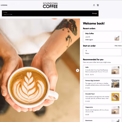 Hands holding a cup of latte with foam art in a Southdown Coffee online ordering interface showing recent orders and recommended items.