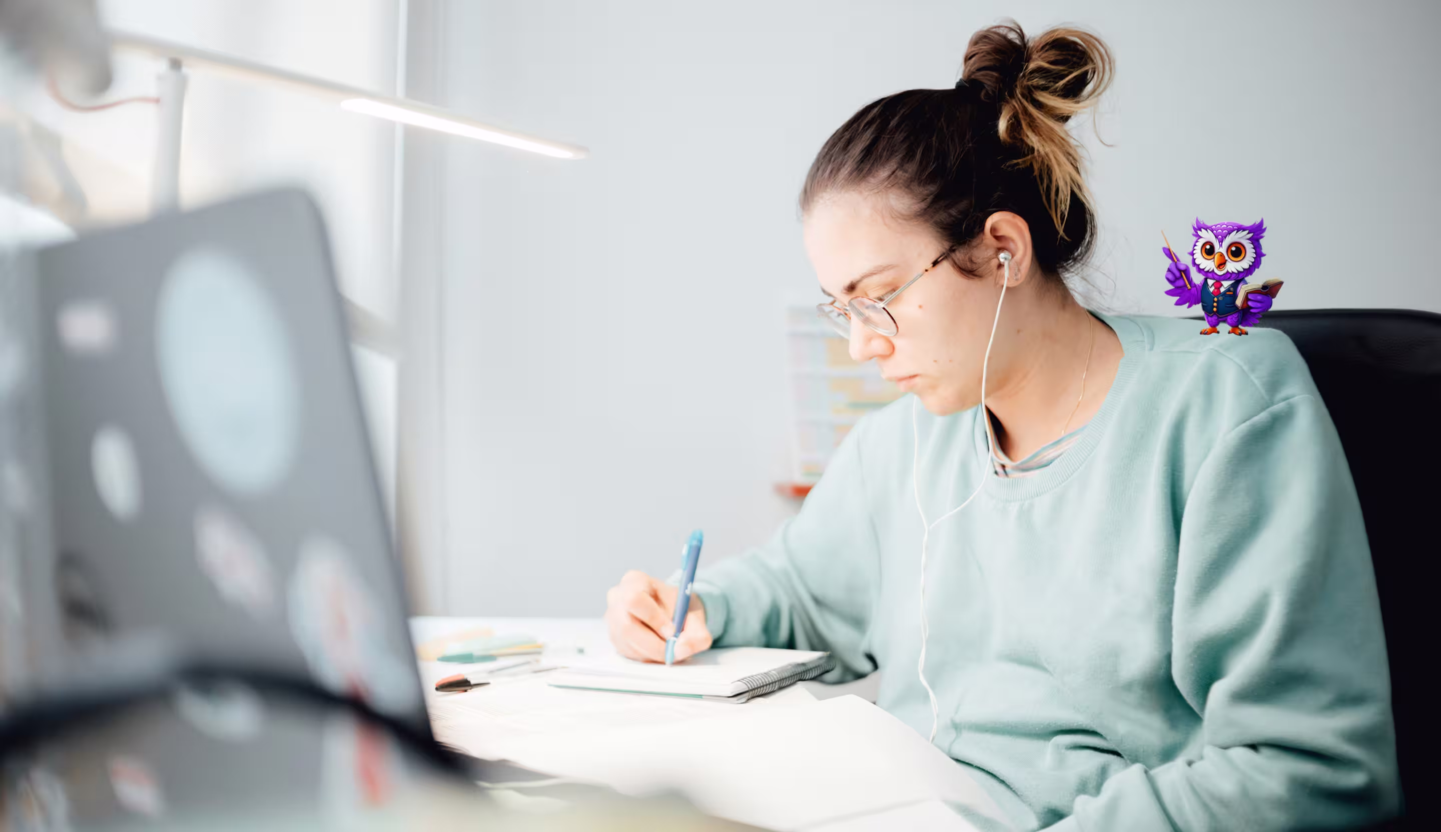 Young woman with glasses and earbuds studying and writing in a notebook at a desk.