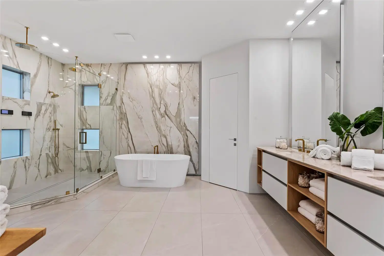 Luxury master bathroom featuring large-format porcelain slab walls, a freestanding bathtub, walk-in shower, floating vanity, and precision tile installation by Artiva Tile.