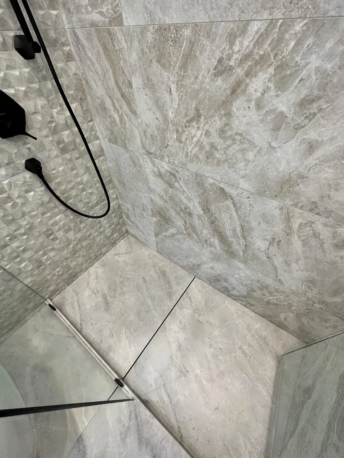 Luxury walk-in shower renovation completed by ArtivaTile in Miami with large-format tile, textured feature wall, and frameless glass enclosure.