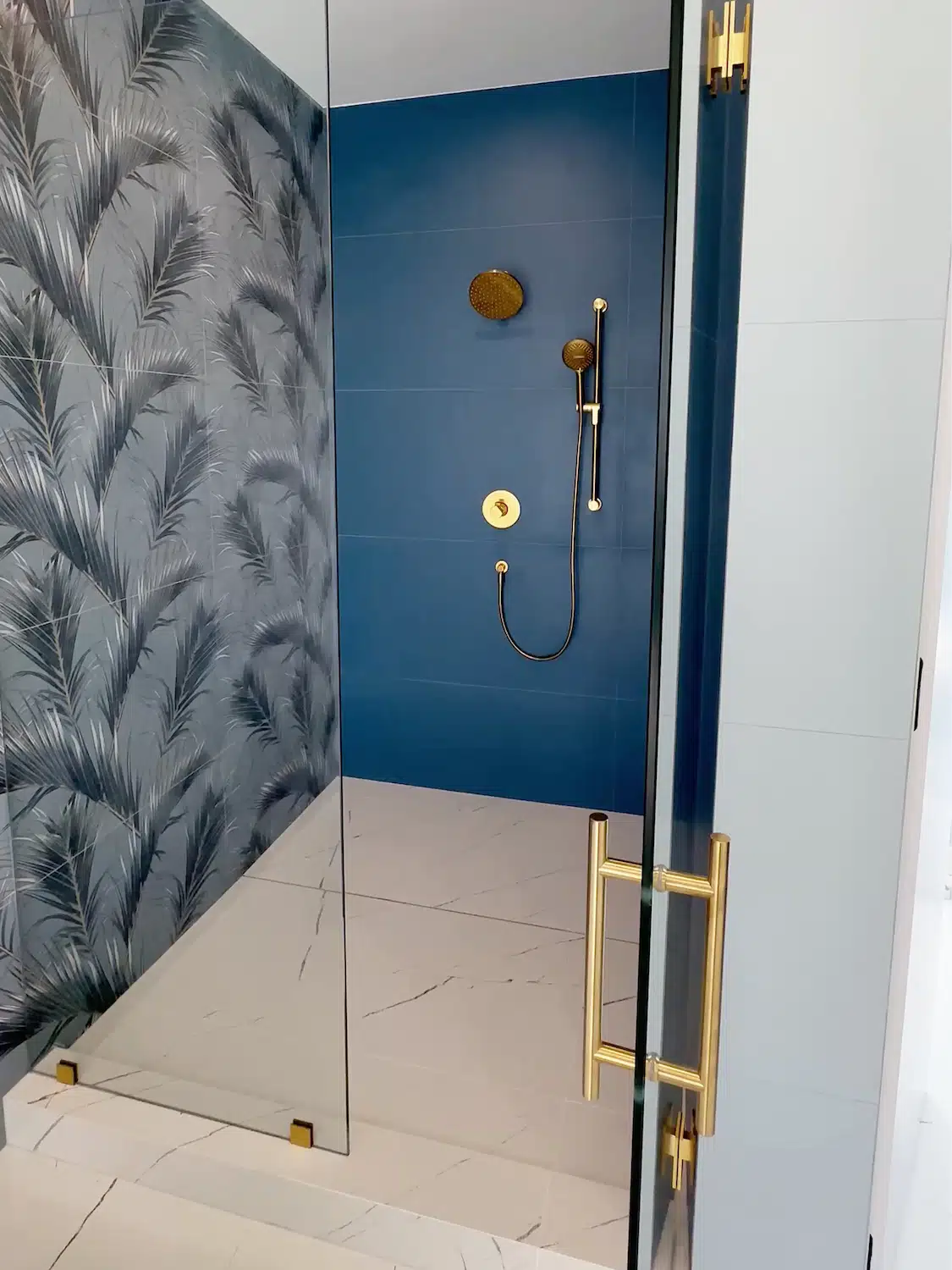 Walk-in shower renovation with blue porcelain tile, gold shower fixtures, and frameless glass enclosure by ArtivaTile.