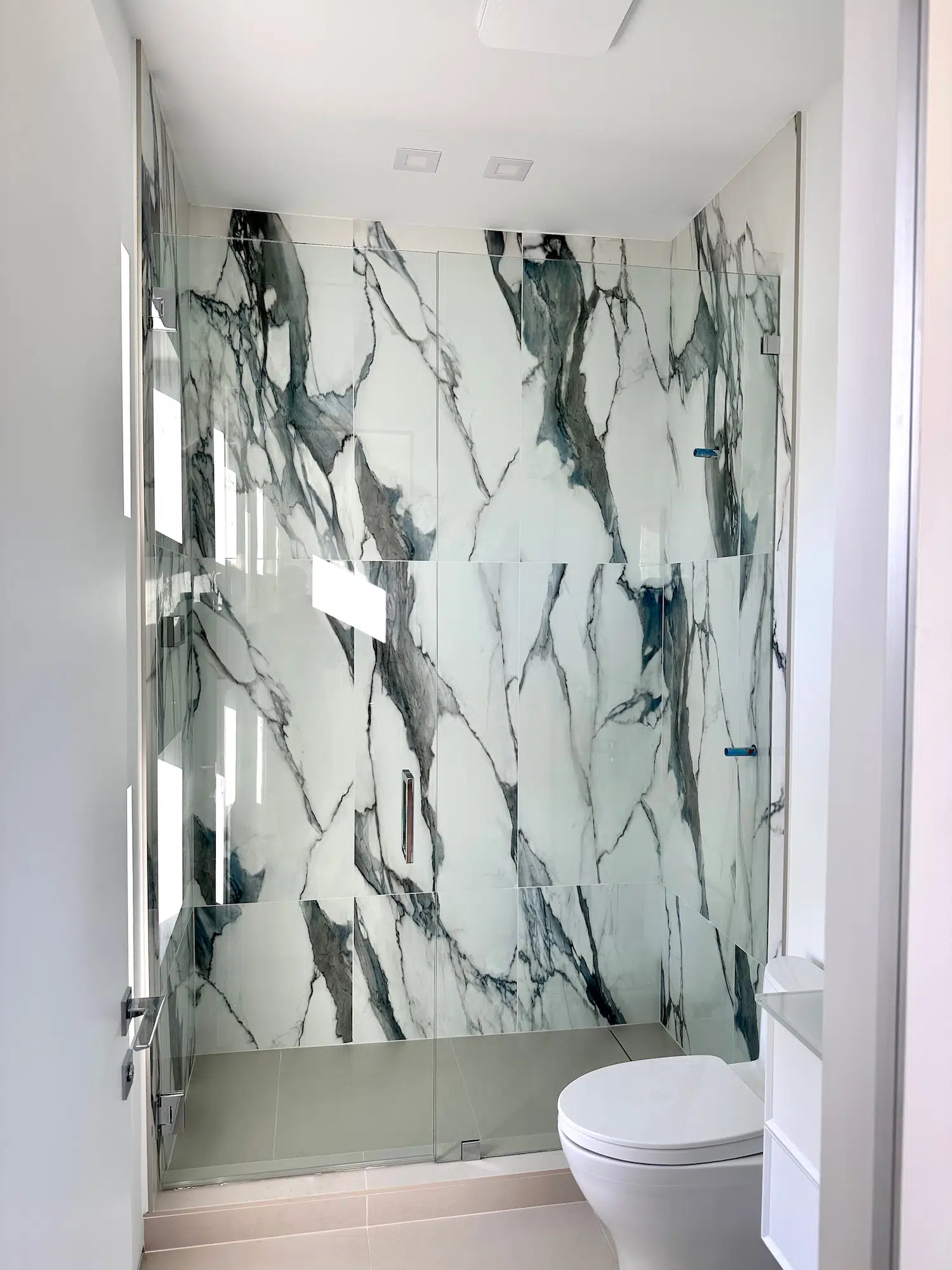 24x48 tile size Modern bathroom shower with oversized marble-look porcelain slabs installation.