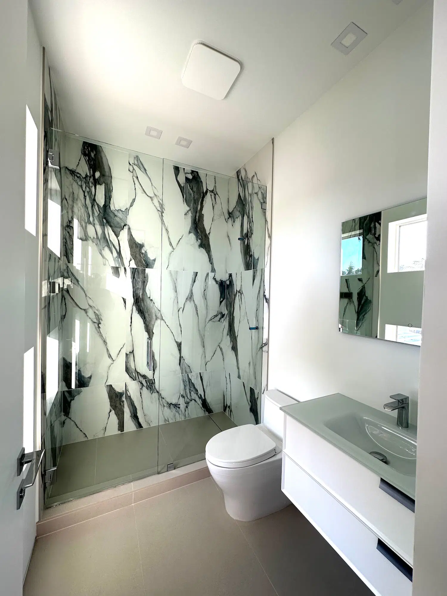 Luxury shower remodel featuring large-format marble-look porcelain tile, frameless glass enclosure, and precision tile installation in Miami.