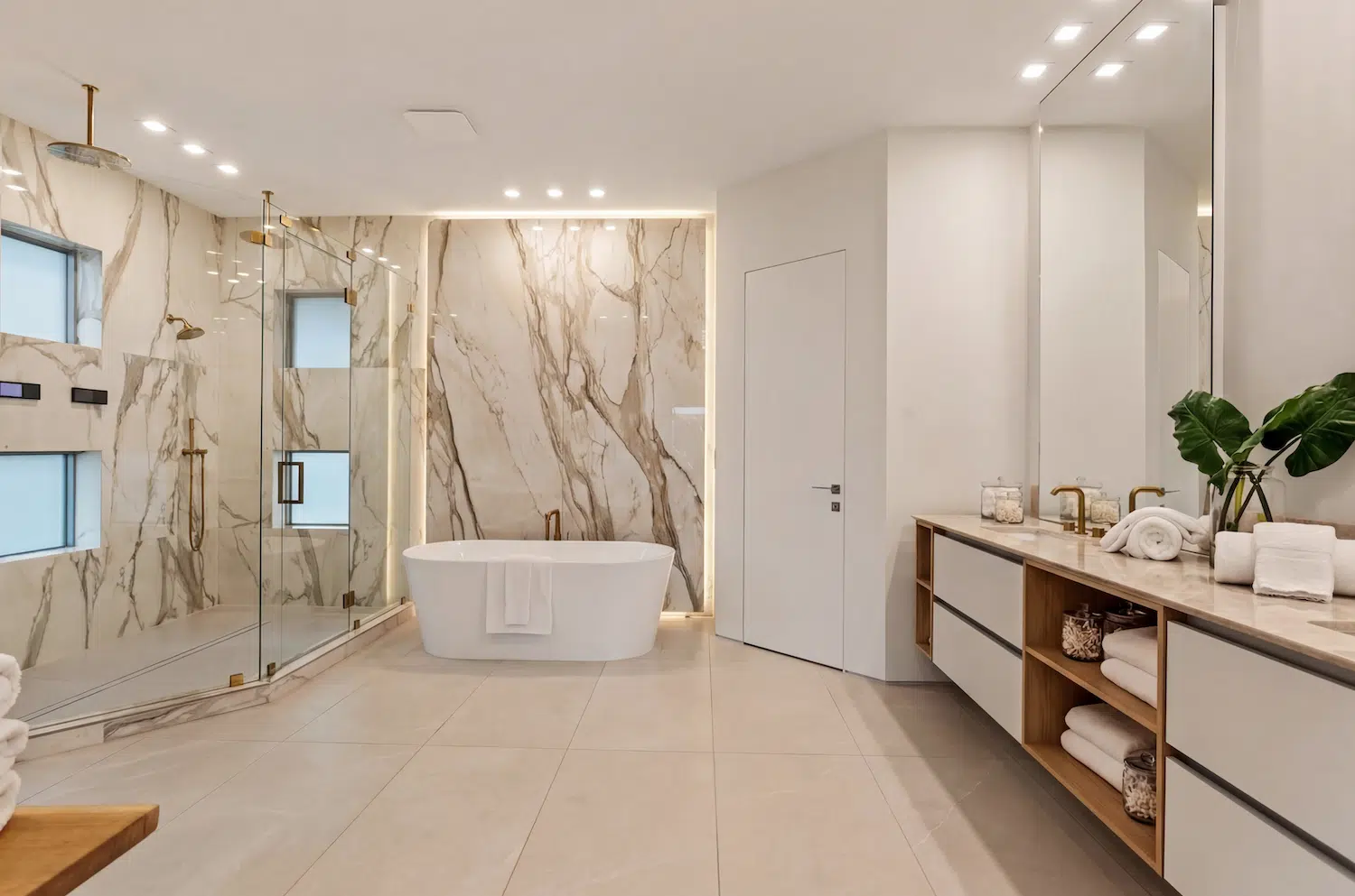 Luxury master bathroom in Fort Lauderdale featuring large-format bookmatched porcelain slabs, frameless glass shower, freestanding bathtub, and custom double vanity installed by ArtivaTile.