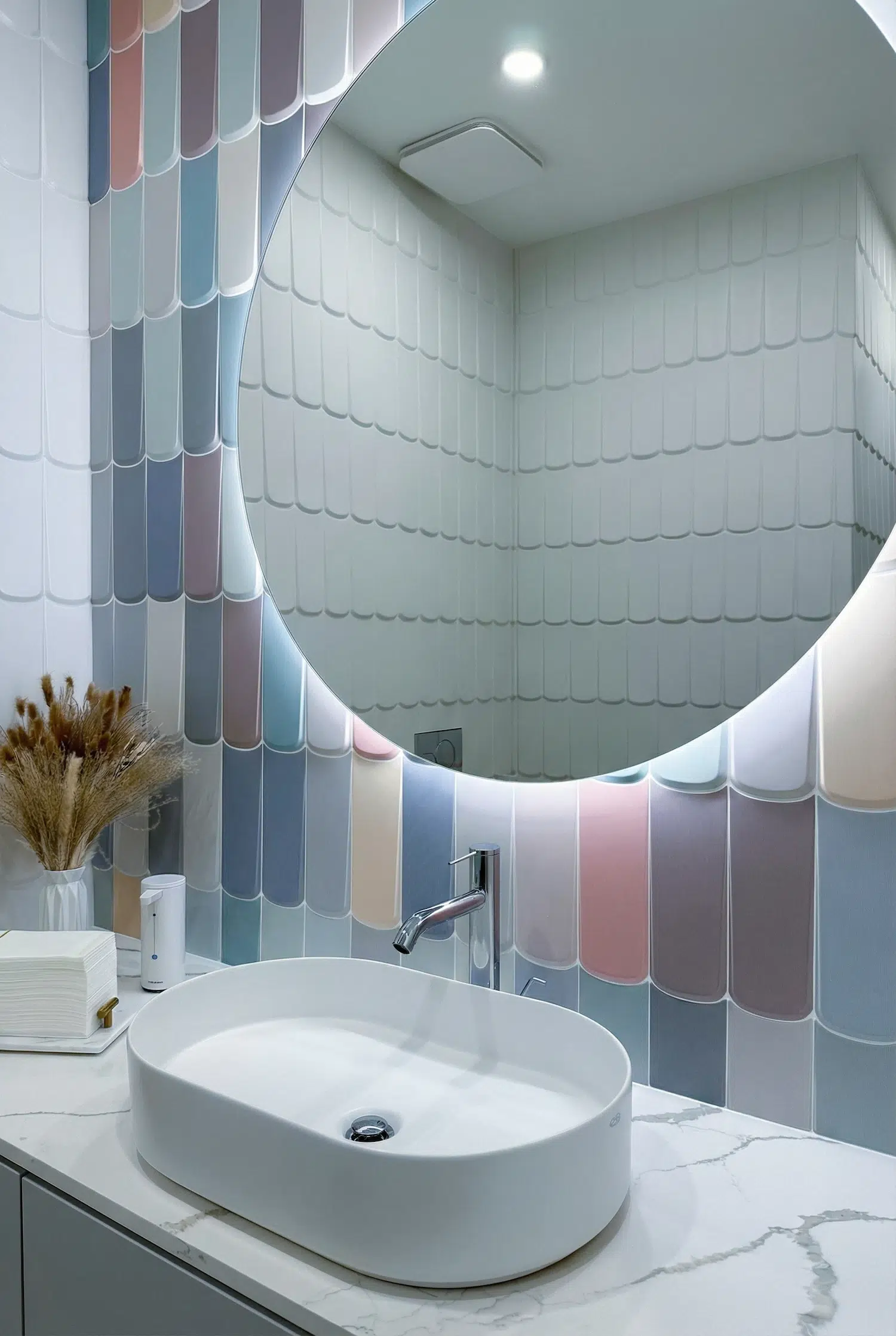 Close-up of decorative pastel fish scale tile accent wall featuring a round illuminated mirror, vessel sink, and contemporary powder room design.