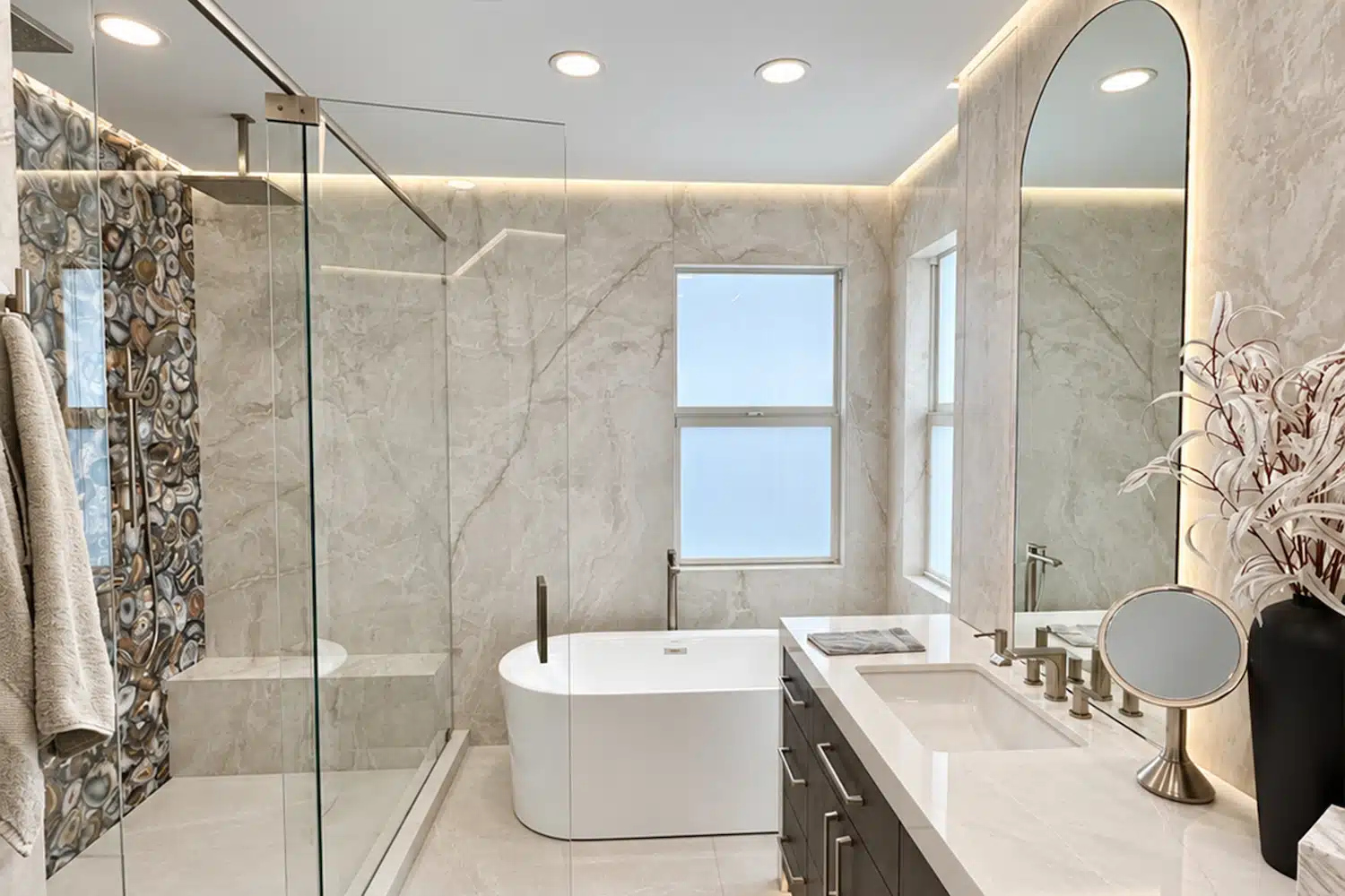 Completed luxury bathroom remodel featuring a glass-enclosed shower, decorative agate tile, freestanding bathtub, large-format porcelain walls, and custom vanity.