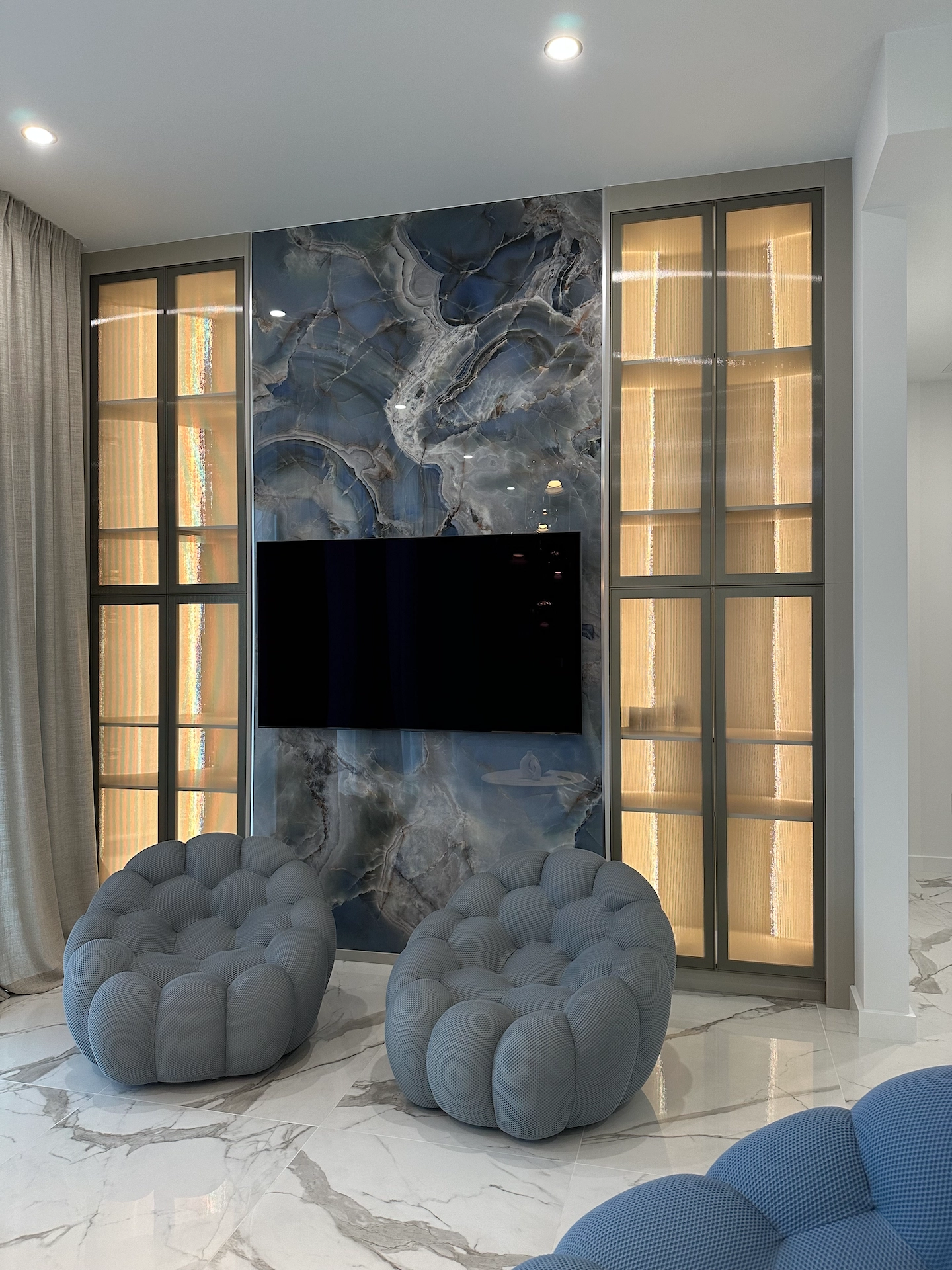 Architectural living room design featuring large-format tile slabs and decorative gold pendant lighting