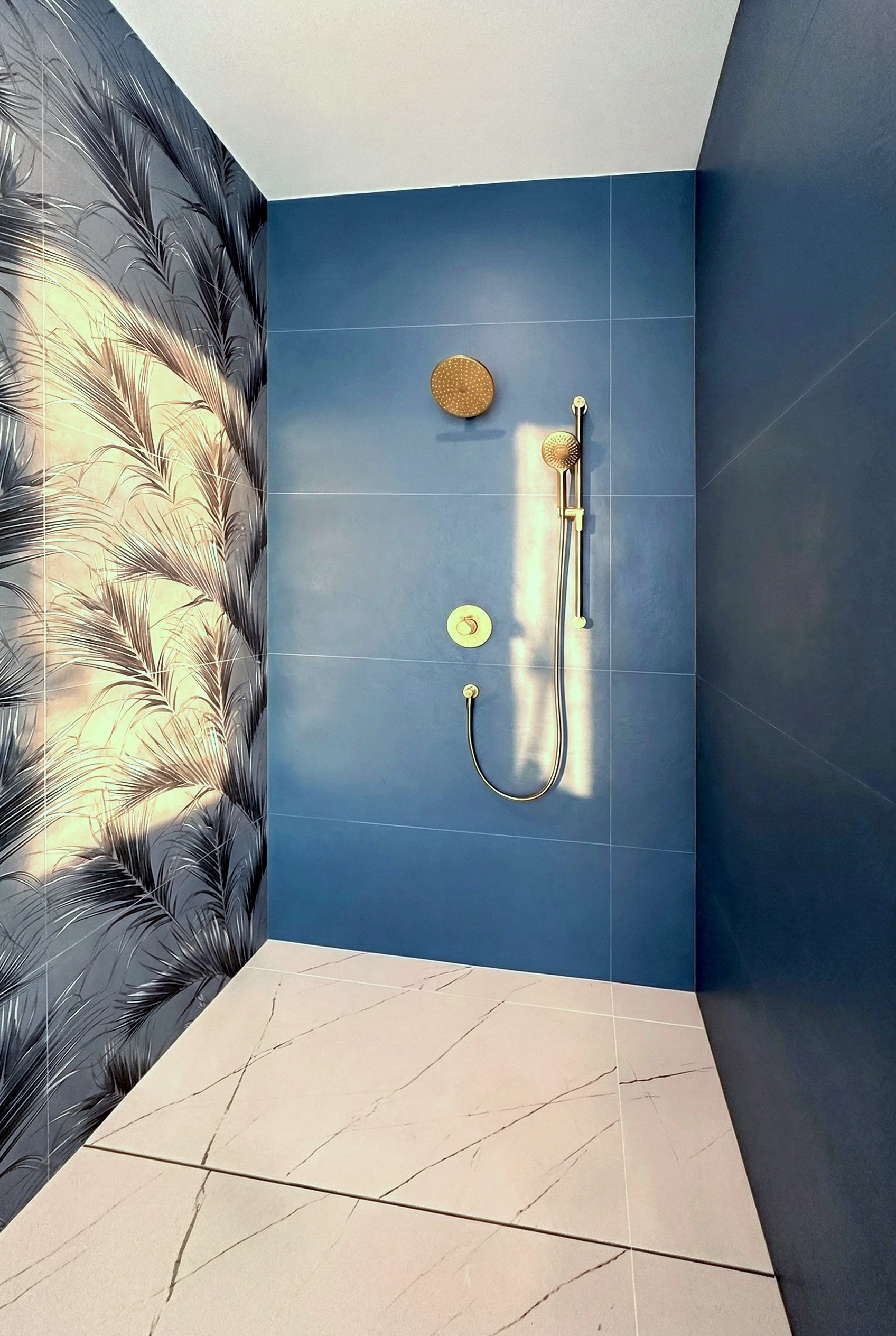 Luxury Miami bathroom with custom blue vanity cabinets, LED backlit mirror, freestanding sinks, gold fixtures, and large-format palmtree tile.