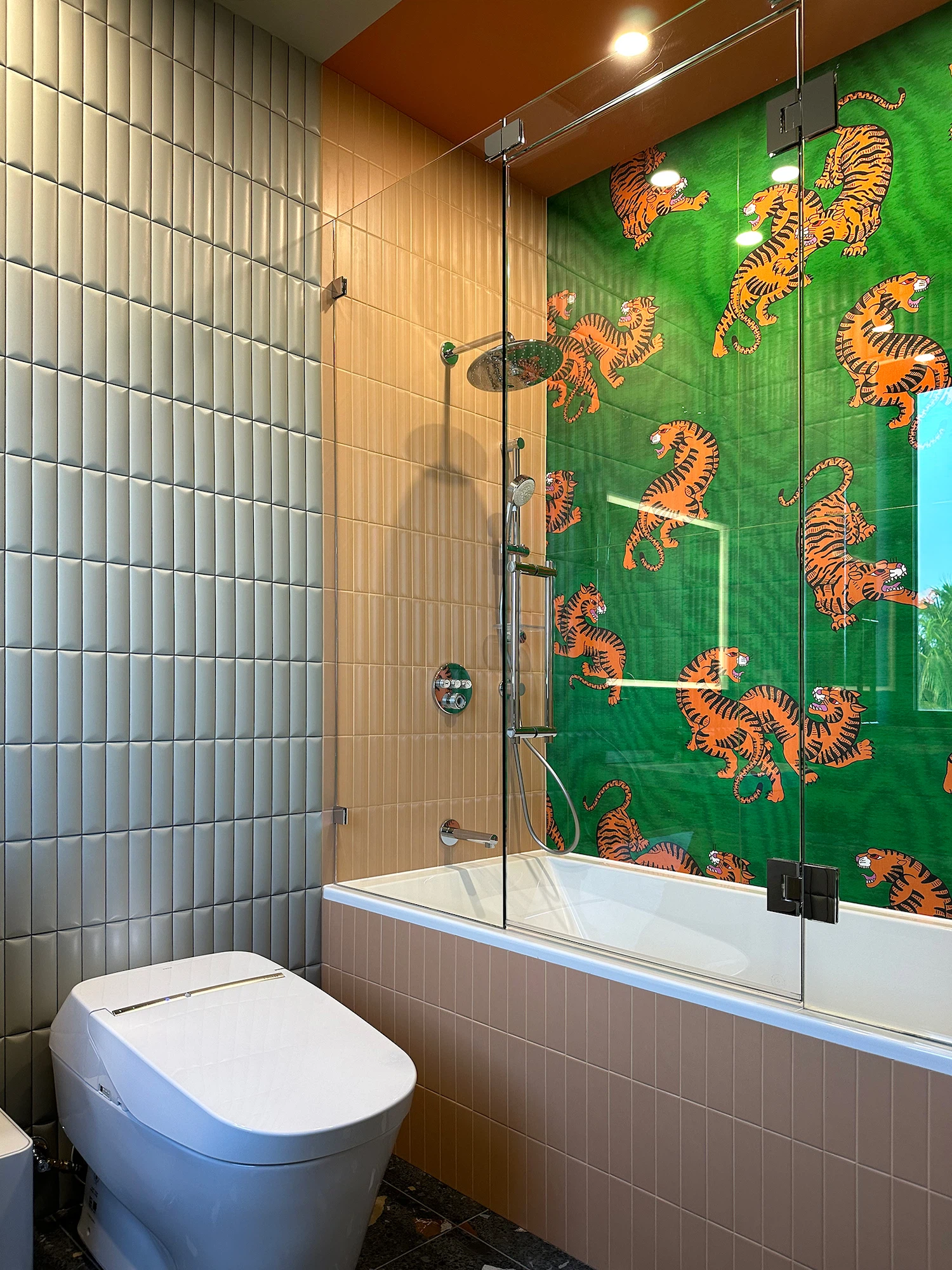 Custom bathroom design with green and orange patterned tile wall and freestanding bathtub