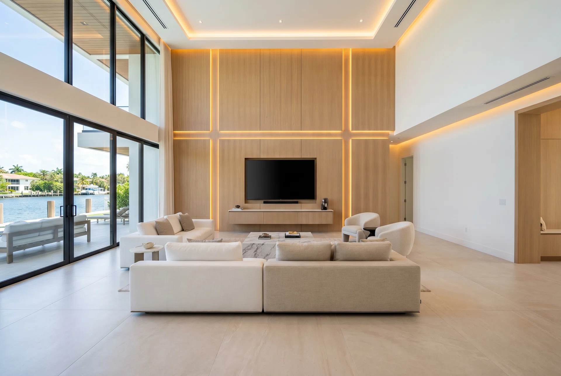 Modern luxury Miami living room with architectural wood panel feature wall, integrated LED lighting, large-format porcelain flooring, double-height ceilings, and waterfront contemporary interior design.