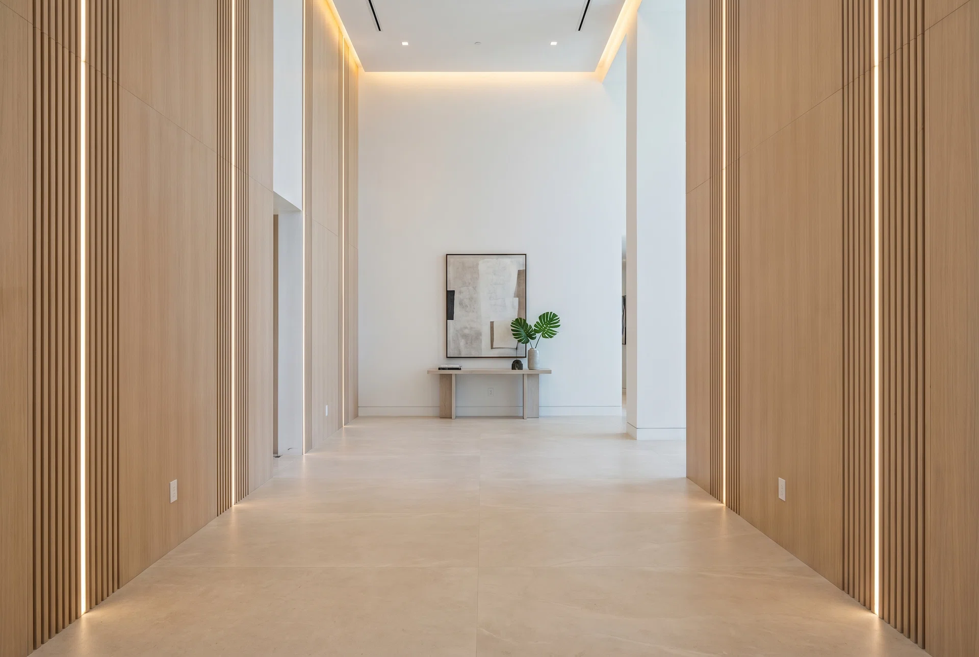 Modern luxury hallway with architectural wood wall panels, vertical slat detailing, integrated LED lighting, large-format porcelain flooring, and minimalist contemporary interior design in Miami.