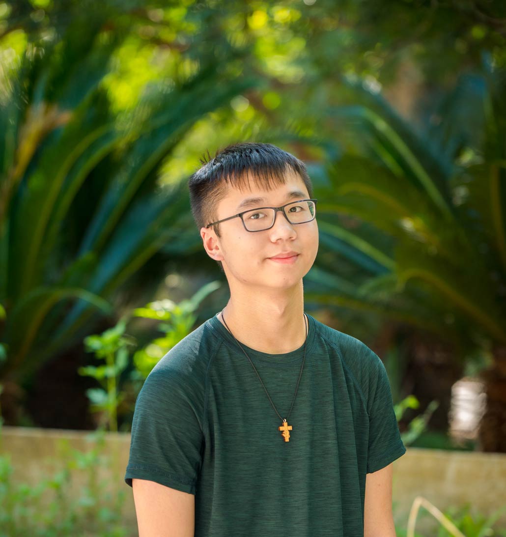 College Beyond student, Kevin Tran, on UNO's campus in front of folliage