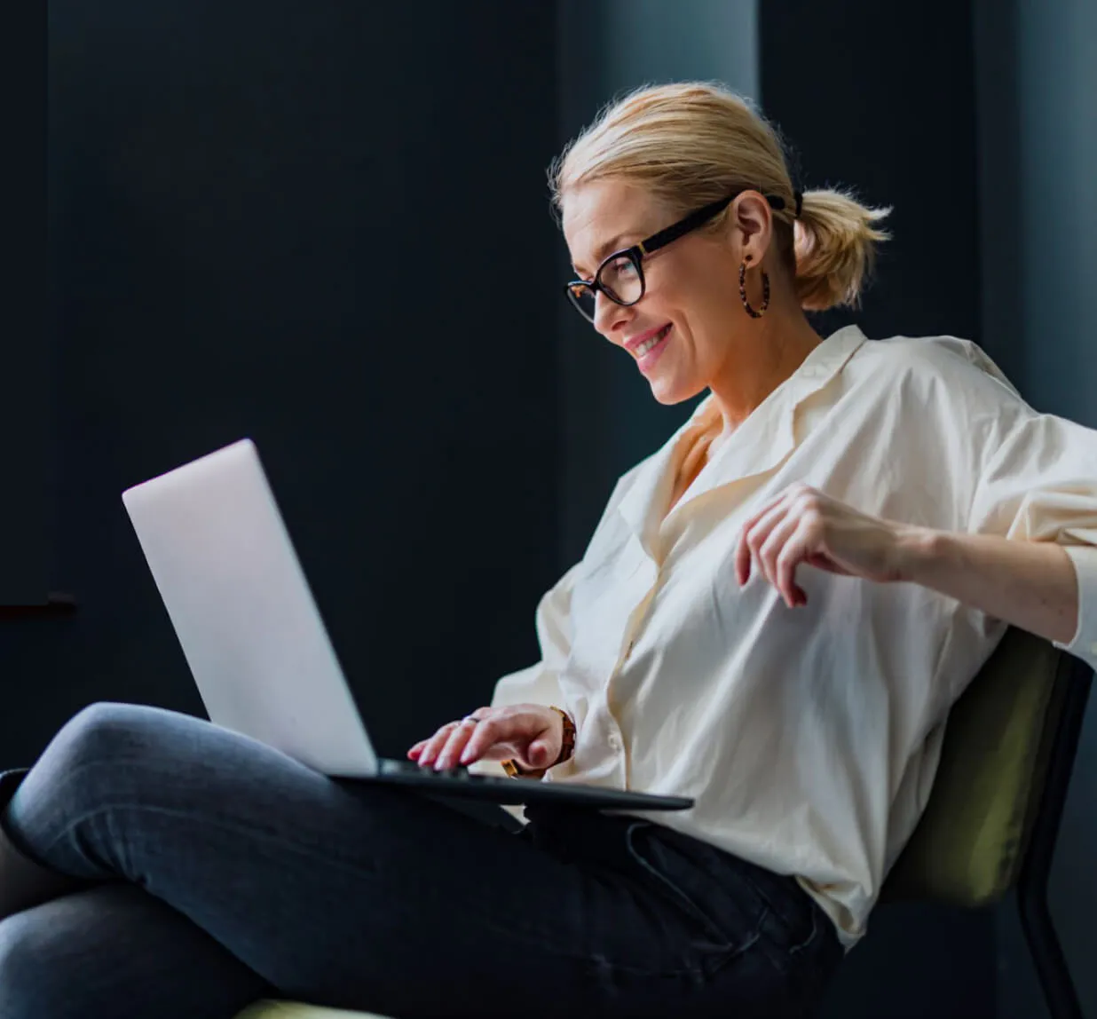 Professional woman in white blouse working on laptop in modern office setting