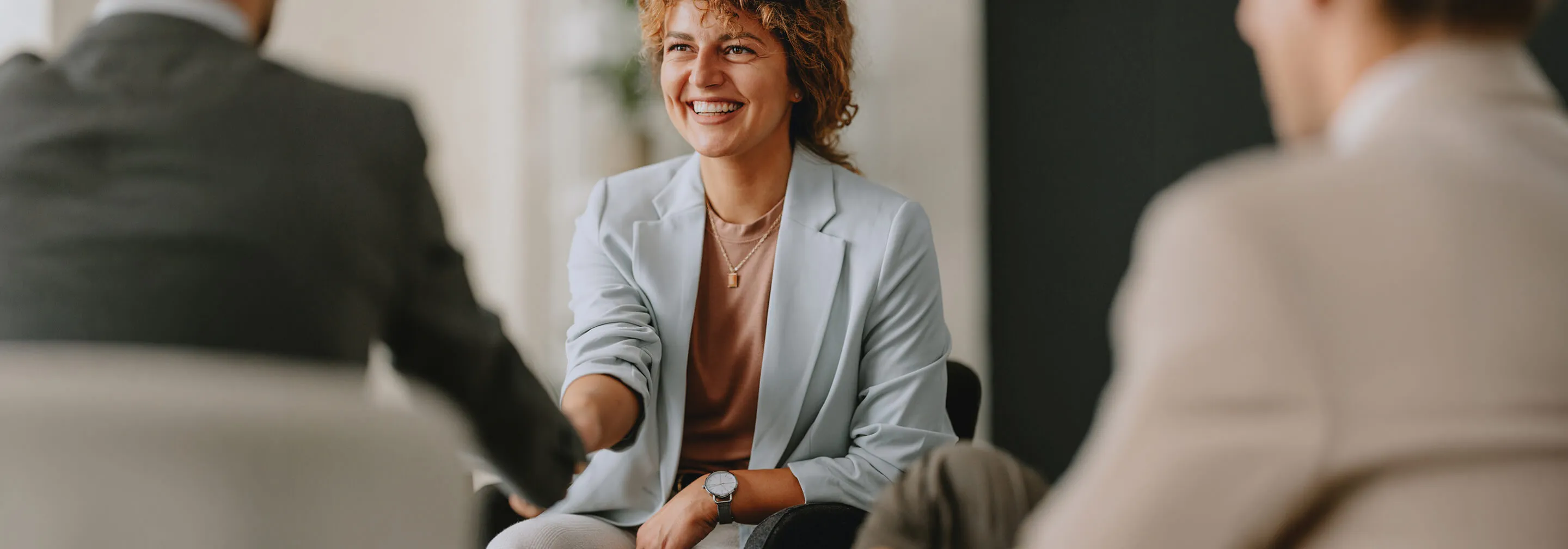 Professional woman in light blue blazer smiling during a client meeting