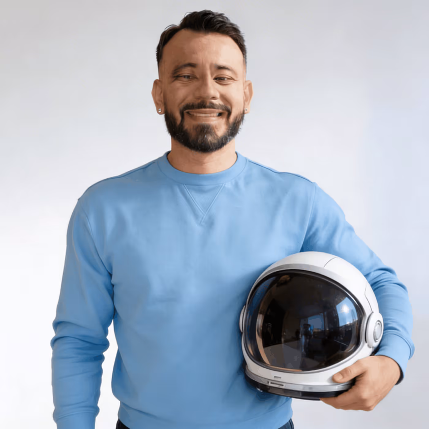 Man in a blue sweatshirt smiling and holding a white space helmet.