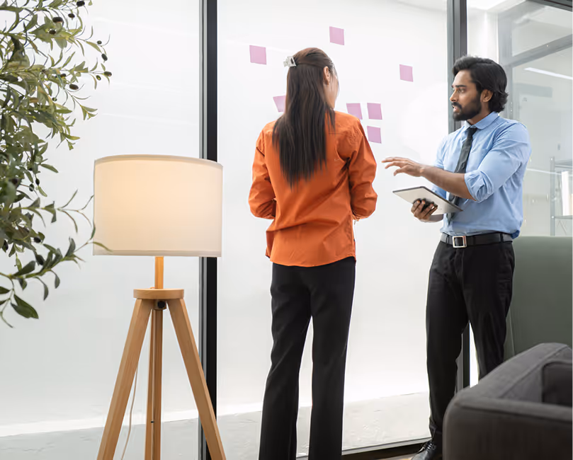 Colleagues standing and talking beside an office whiteboard