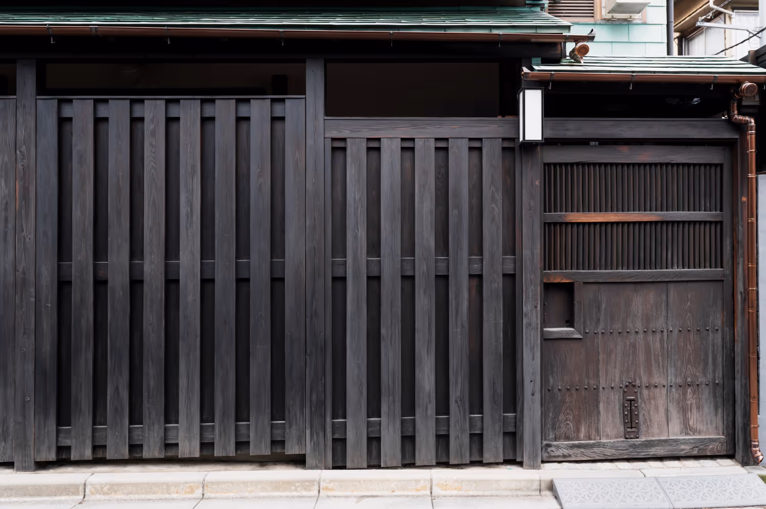 Traditional Japanese wooden gate and fence with vertical slats and a small roof.