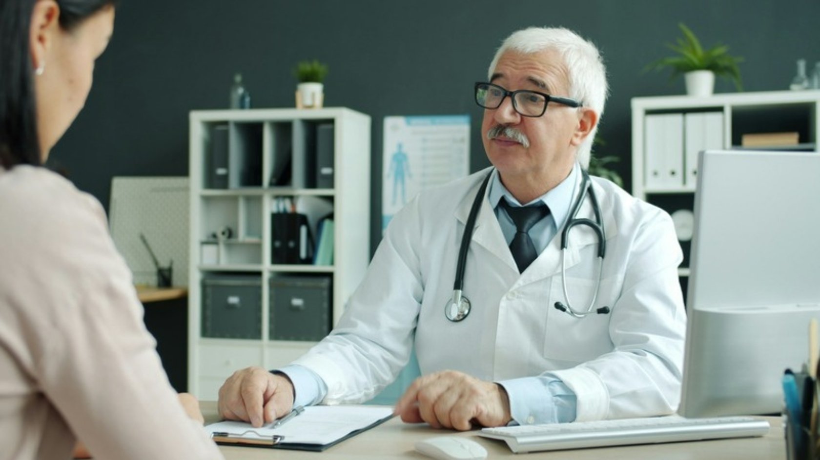 Doctor talking with a patient across a desk in a consulting room