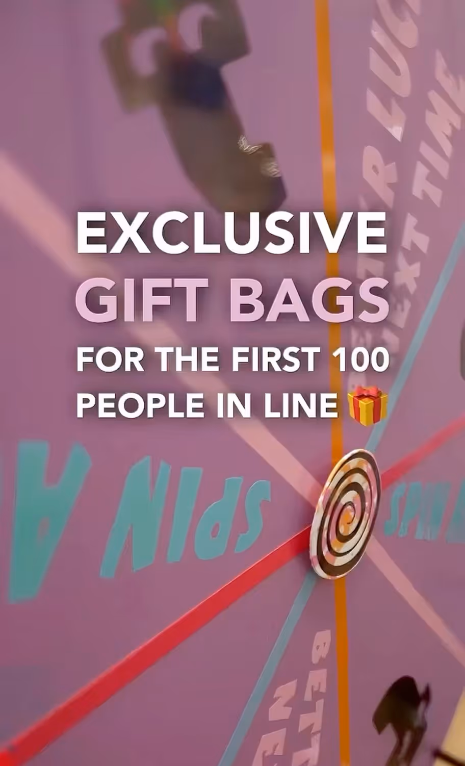 Promotional text offering exclusive gift bags for the first 100 people in line, displayed over a colorful spinning wheel background.