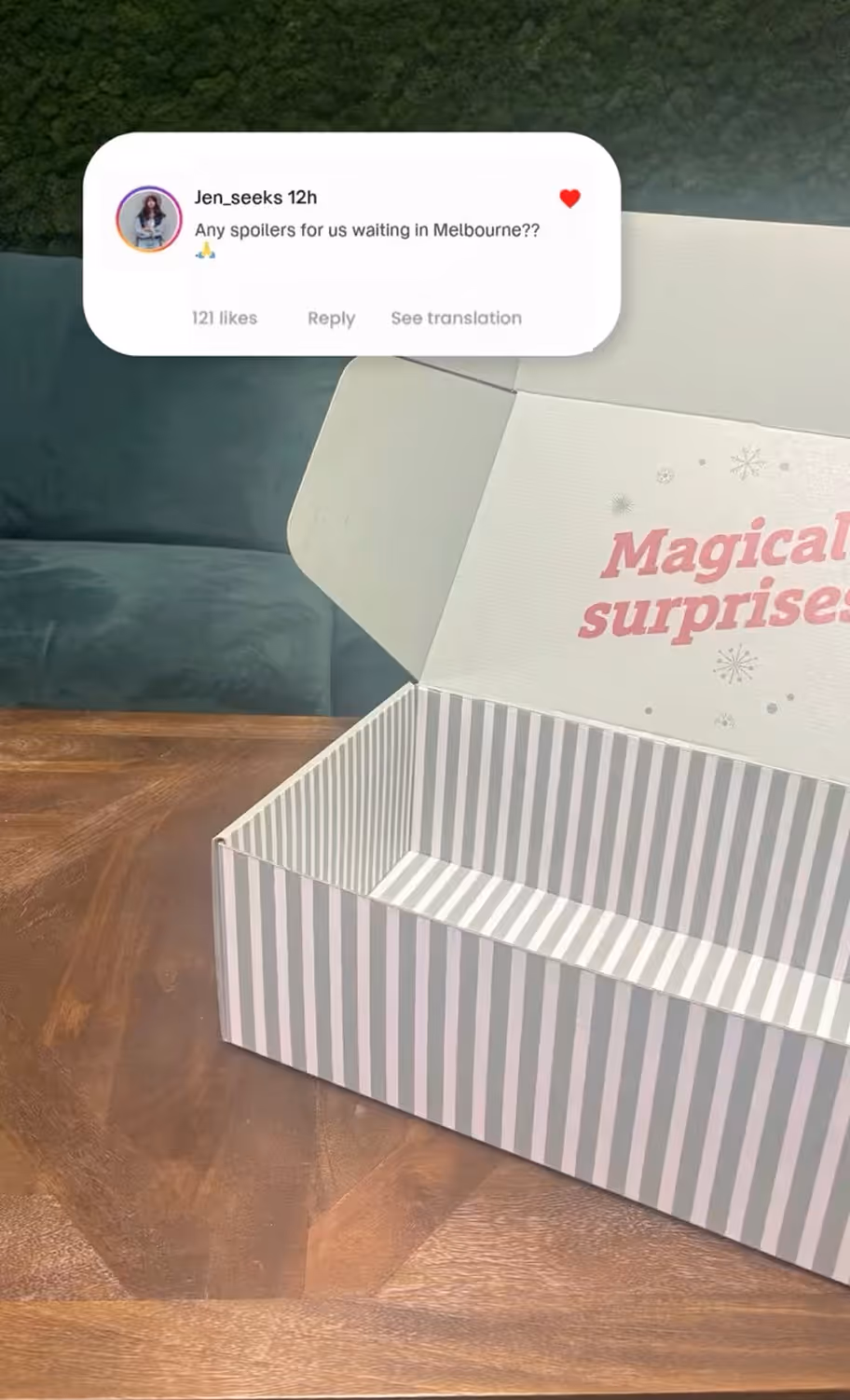 White and gray striped open gift box on a wooden table with the words 'Magical surprises' printed inside the lid.