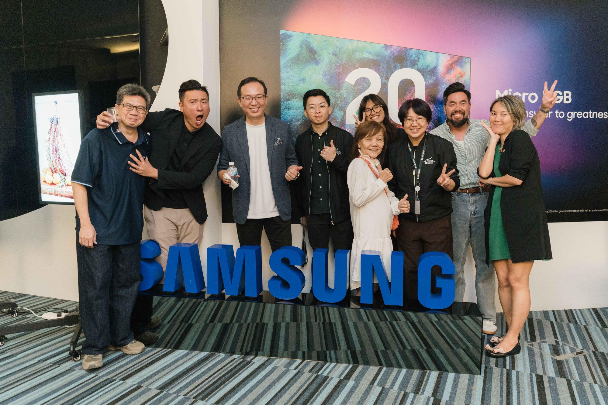 Members pose by the Samsung sign