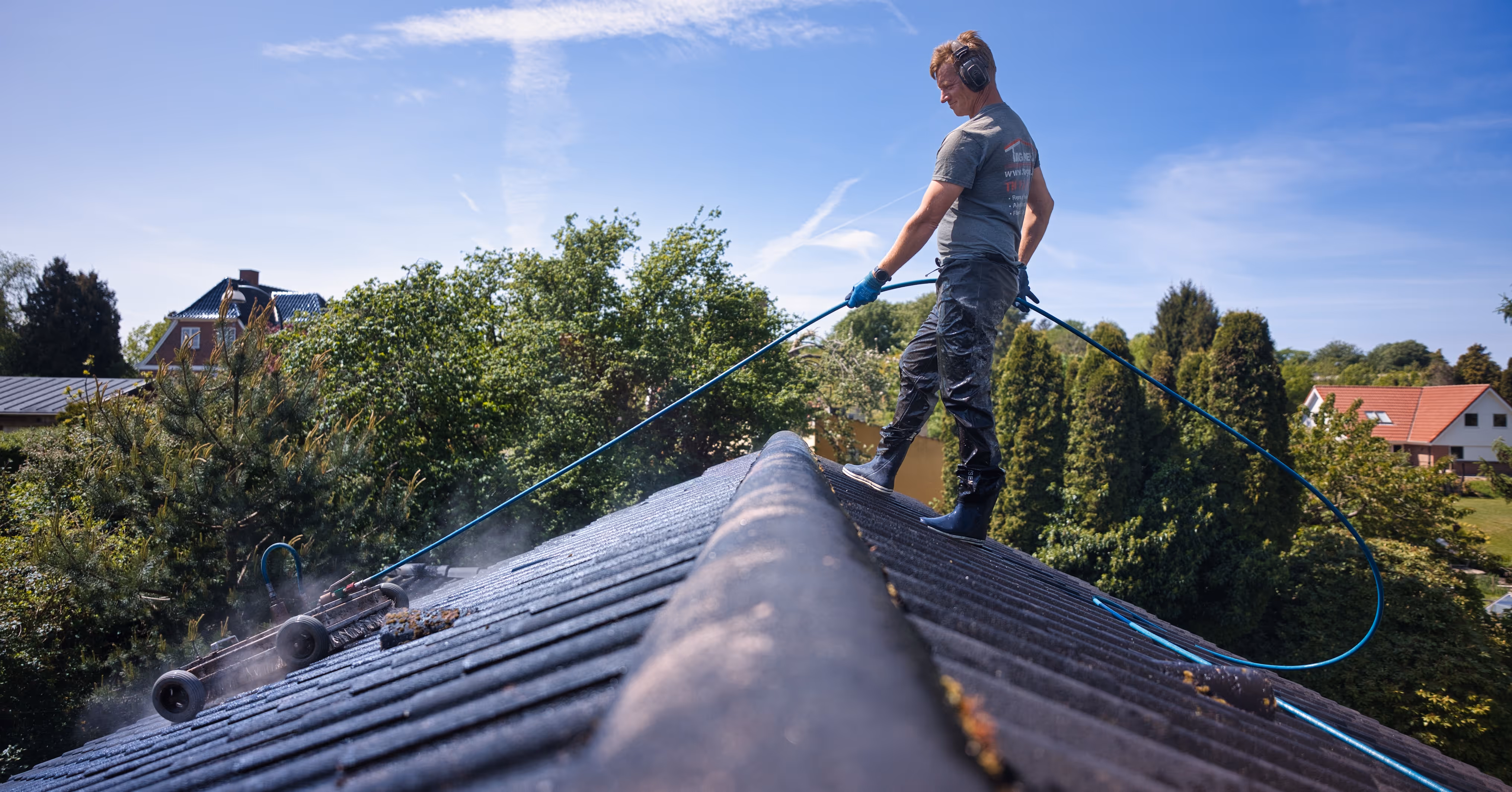 Mand renser tag med højtryksrenser iført hørebeskyttelse og gummistøvler.