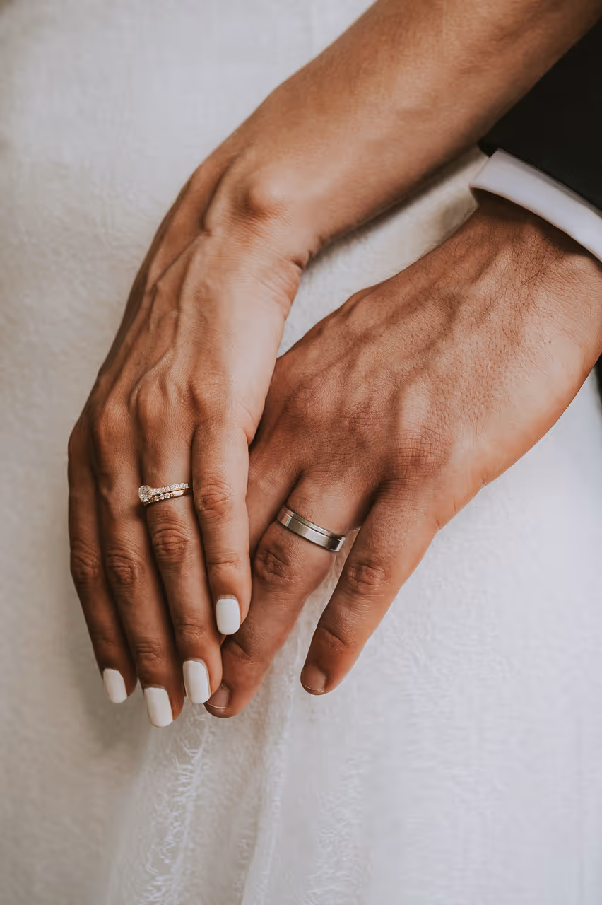 Deux mains entrelacées, une femme porte une bague en or avec un gros diamant.