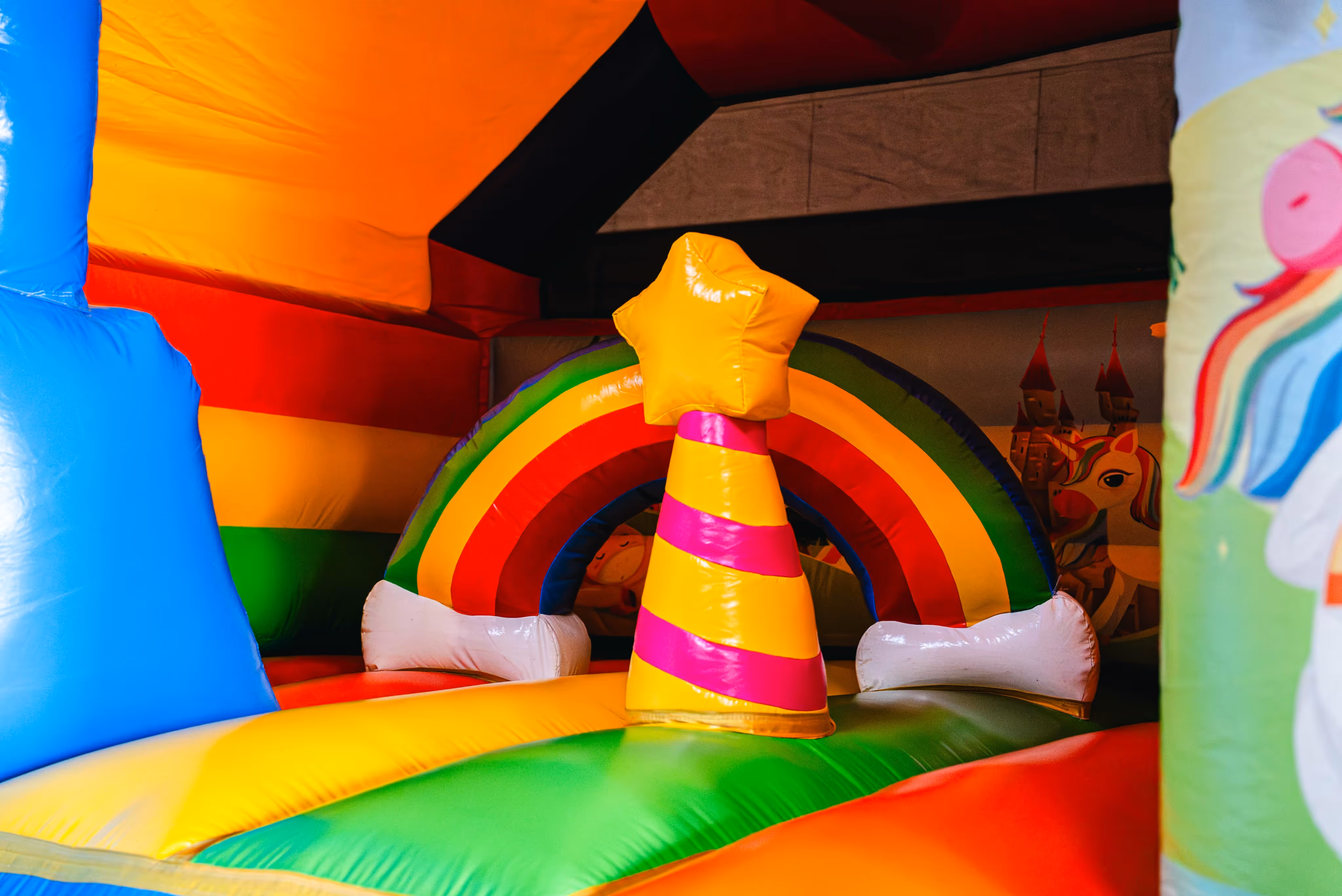Bannerafbeelding met een kleurrijk springkasteel in regenboog- en fantasiethema, gebruikt als achtergrond bij de titel “Inspiratie voor jouw feest”.