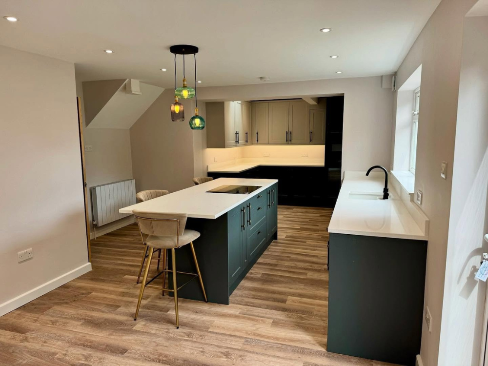 Modern kitchen with a white island, beige bar stools, pendant lights, wood floor, and dark cabinets.