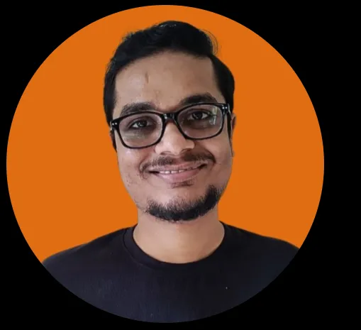 Man with glasses and short beard smiling in front of an orange background.