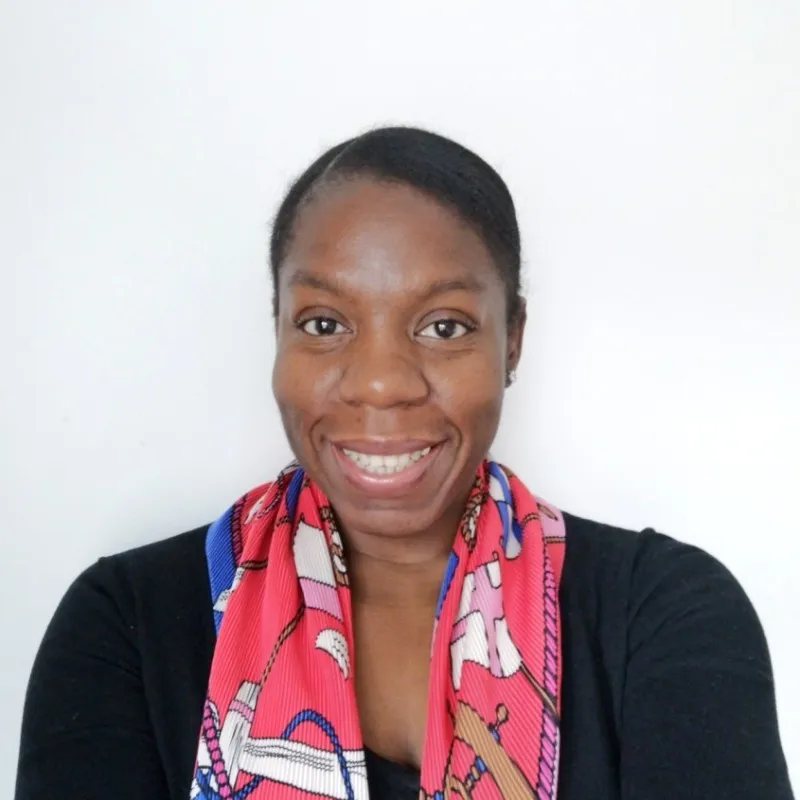 Smiling woman with dark skin, black hair, wearing a black top and a colorful red scarf.