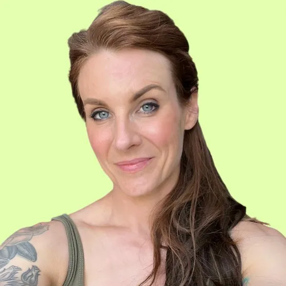 Woman with long brown hair and blue eyes smiling against a light green background.