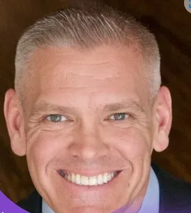 Close-up of a middle-aged man with short gray hair smiling.
