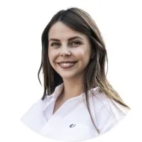 Smiling woman with long dark hair wearing a white collared shirt against a white background.