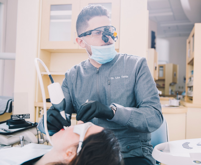Dentist wearing protective glasses and mask treating a patient in a dental clinic.