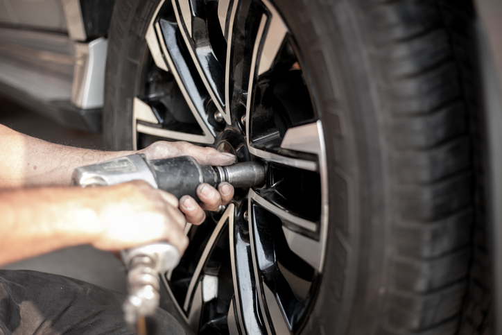 Decorative- Bild zeigt exemplarisch wie ein Mechaniker mit einem Druckluftschrauber ein Rad lockert schraubt.