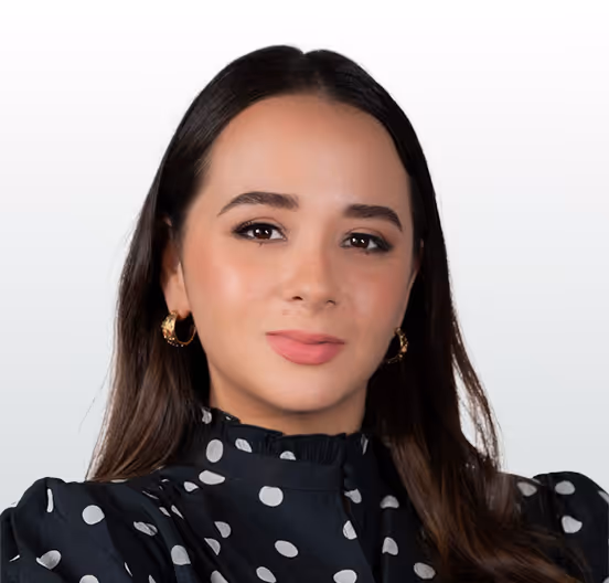 Portrait of a woman with long dark hair, wearing gold hoop earrings and a black blouse with white polka dots.
