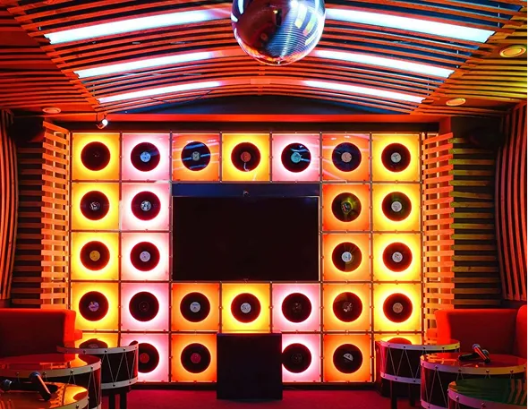 Colorfully lit wall display featuring multiple vinyl records around a central black screen in a modern music-themed room.