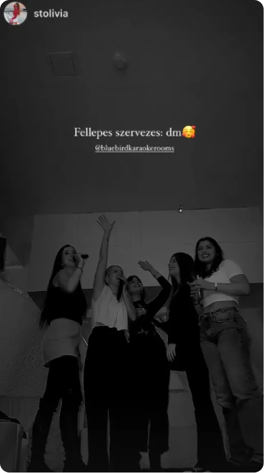 Seven people posing and singing in a karaoke room with starry ceiling decor, one person holding a head mask prop.