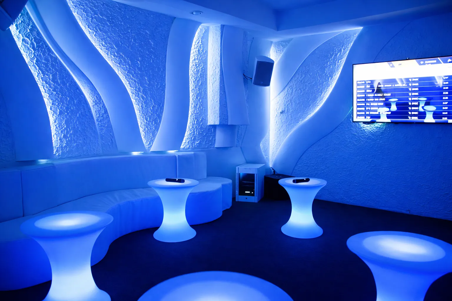 Chic lounge with red velvet tufted sofa, mirrored wall, and tables holding ice bucket with drinks and glassware.