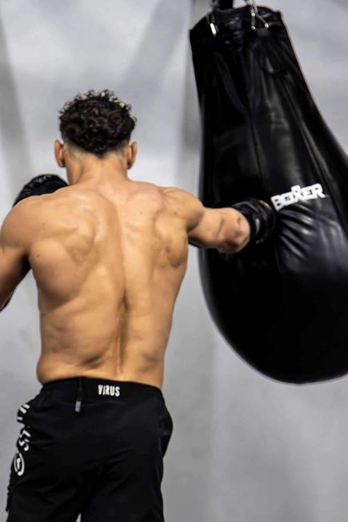 Personal trainer throwing a punch on a heavy bag during boxing training