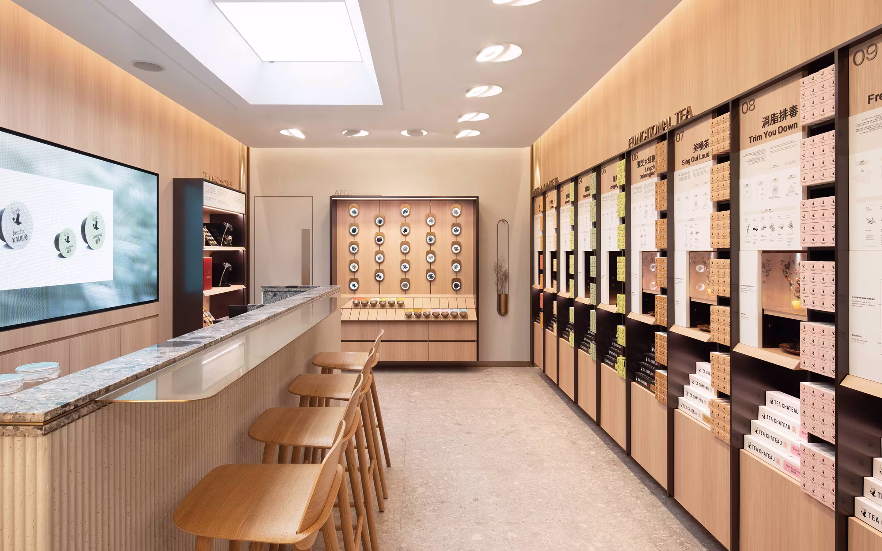 Modern tea shop interior with wooden bar stools, a marble counter, and shelves displaying various teas labeled as functional tea.