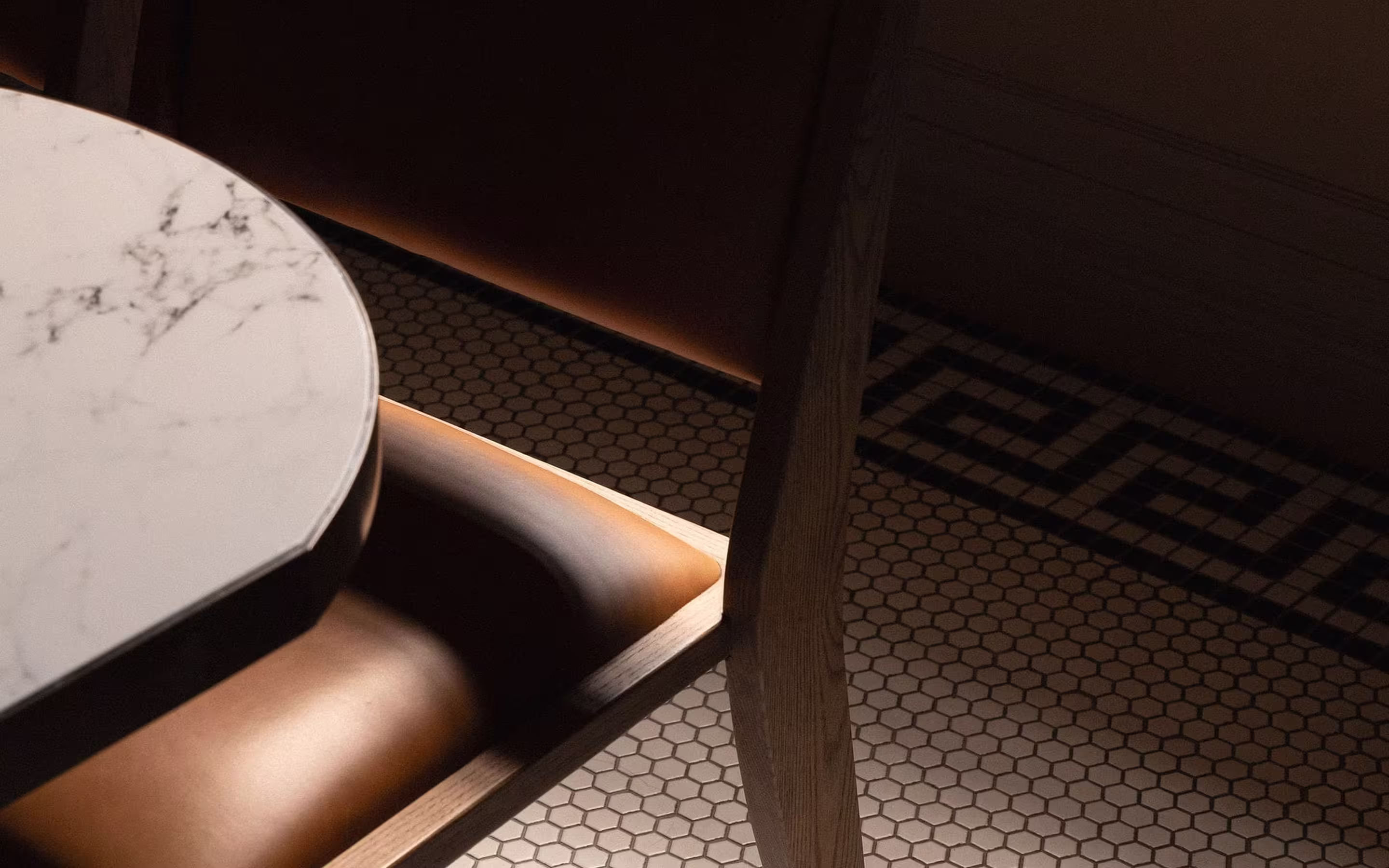 Close-up of a marble tabletop next to a brown leather chair with hexagonal tile floor featuring a decorative border.