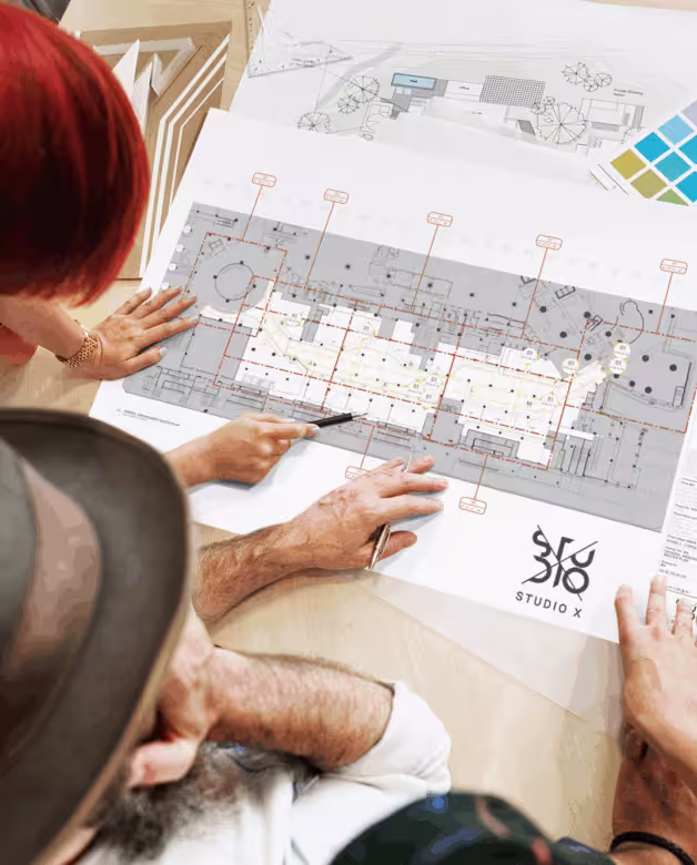 Two people reviewing architectural blueprints on a table with a color swatch nearby.