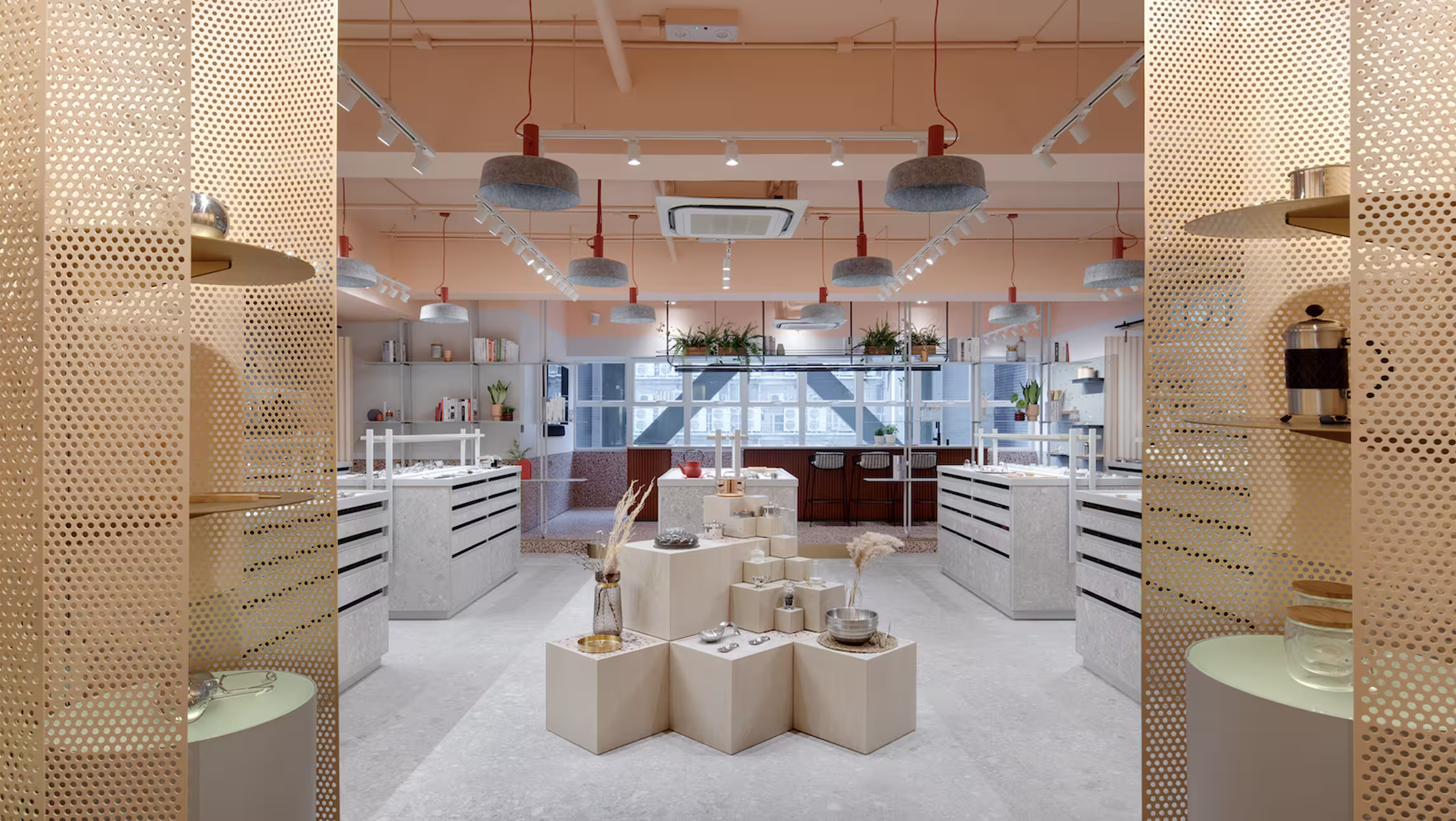 Modern retail store interior with geometric display pedestals and pendant lighting under a peach ceiling.