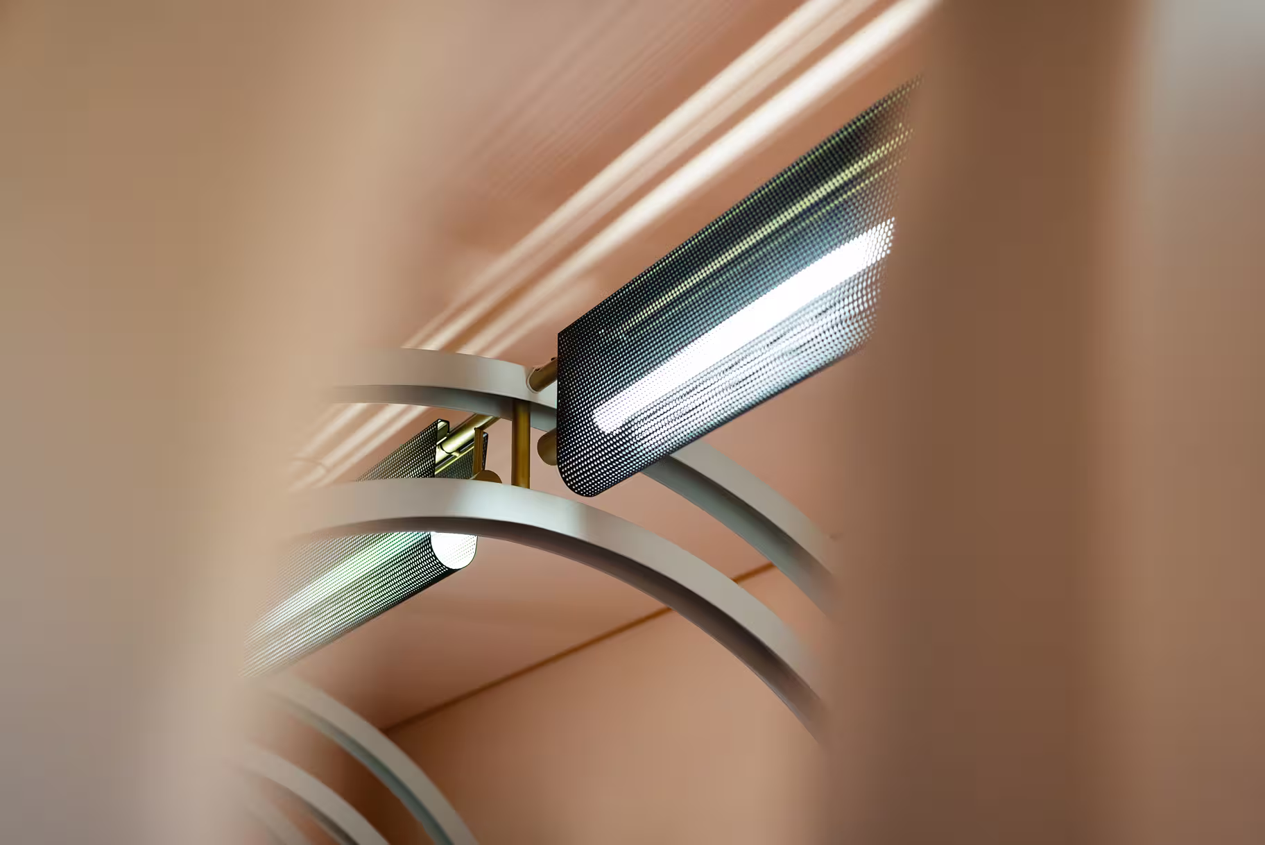 Close-up of modern ceiling light fixtures with curved metal arms and perforated black shades.